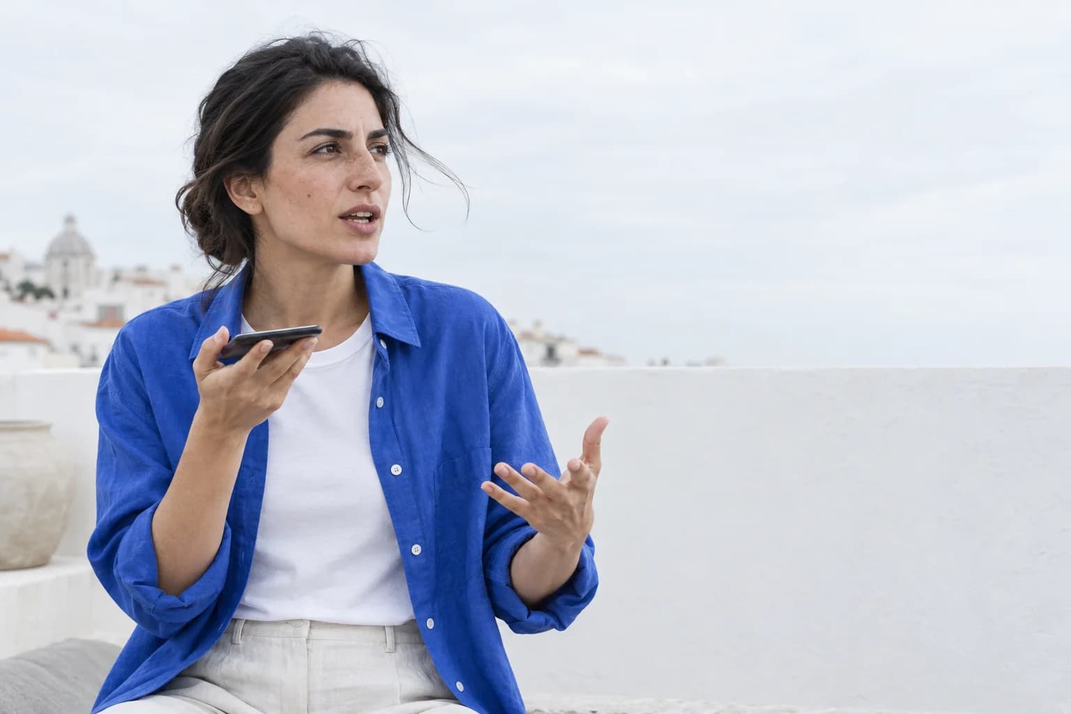 On a white rooftop, she answers a question out loud into her phone.